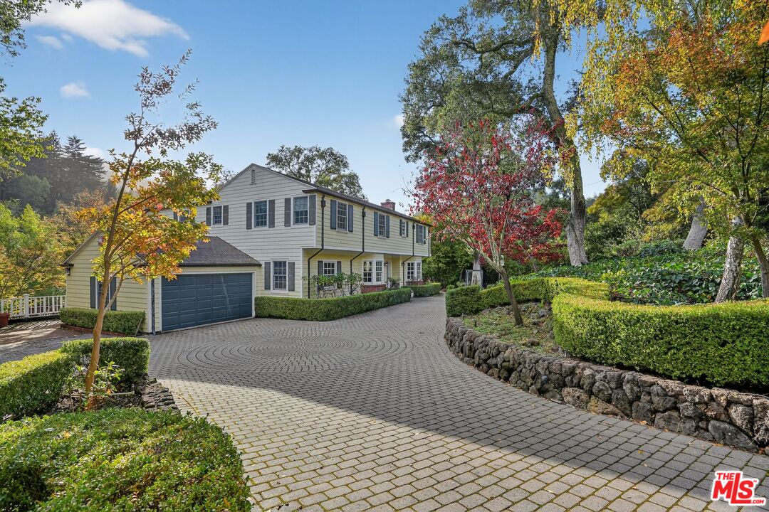a front view of a house with a garden and trees