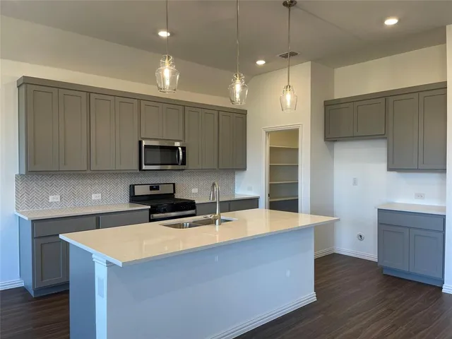 a kitchen with a sink stove top oven and refrigerator