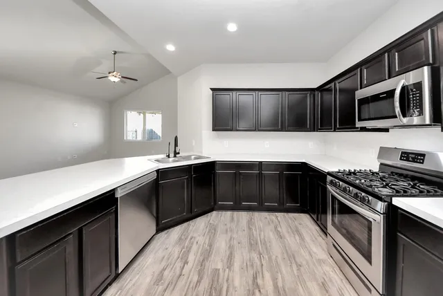 a kitchen with stainless steel appliances a sink dishwasher a stove top oven a refrigerator with island and chairs