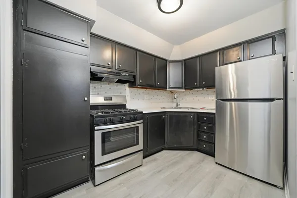 a kitchen with a refrigerator a stove top oven and cabinets