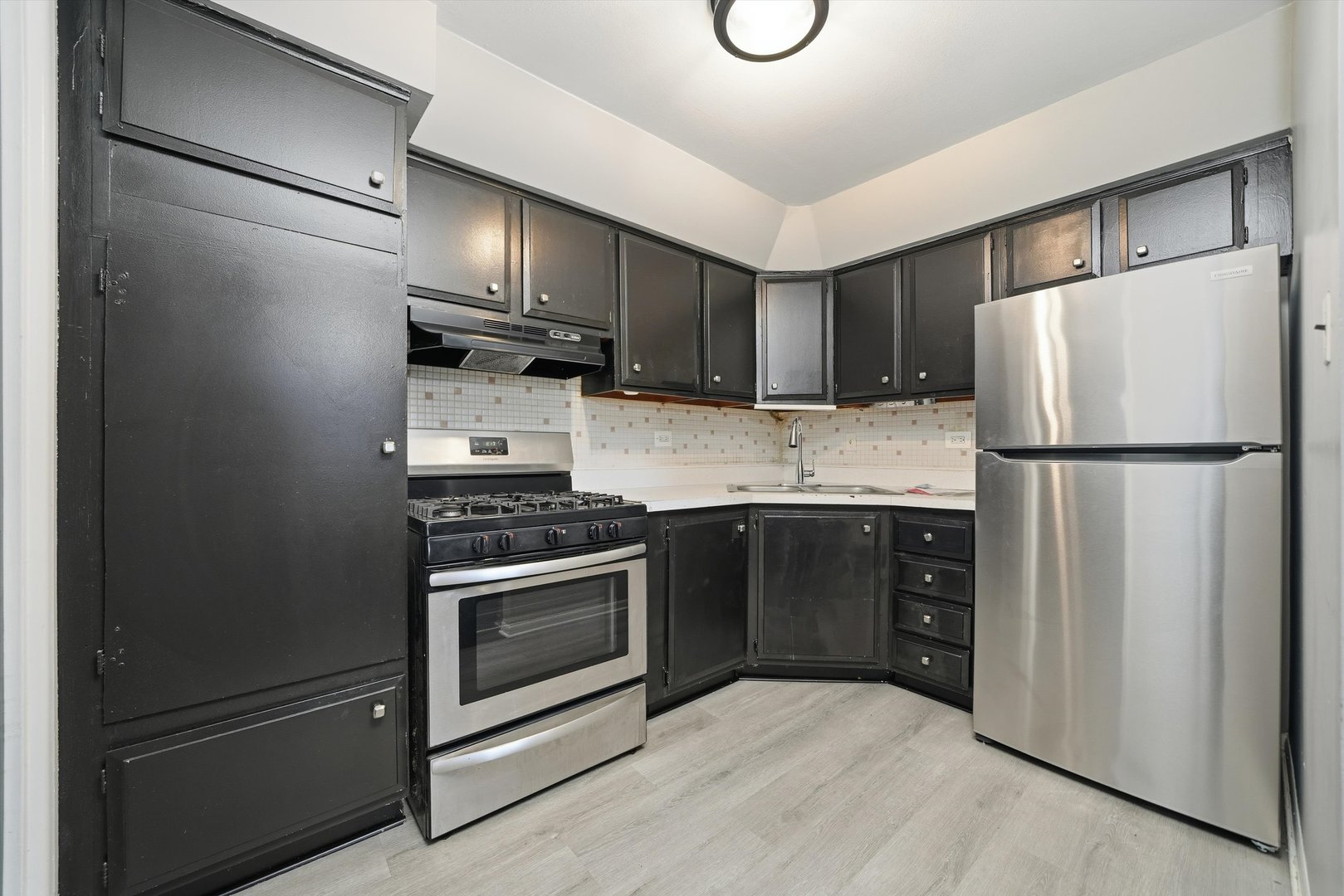 2153 East 87th Street Chicago, IL 60617 - Photo 3 of 9 a kitchen with a refrigerator a stove top oven and cabinets