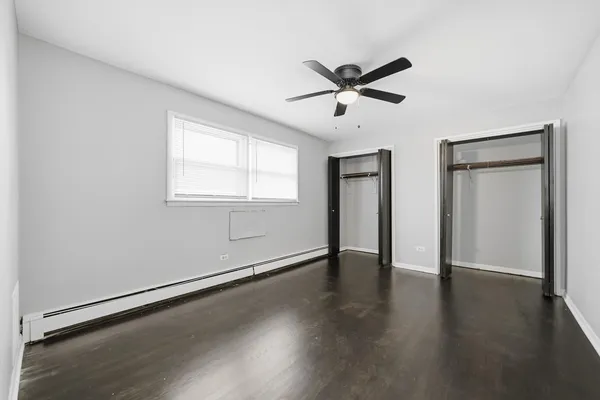 an empty room with wooden floor closet and windows