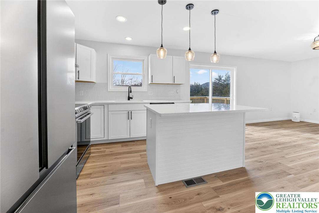 5693 Neola Road Stroudsburg, PA 18360 - Photo 11 of 30 a kitchen with stainless steel appliances granite countertop a sink a stove a refrigerator and white cabinets with wooden floor