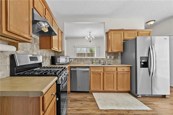 a kitchen with stainless steel appliances granite countertop a stove a refrigerator a sink dishwasher and wooden cabinets with wooden floor
