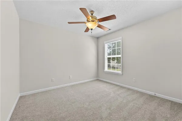 a view of an empty room with a ceiling fan and window