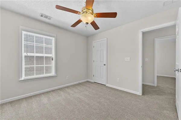an empty room with windows and fan