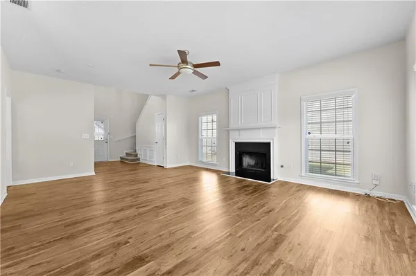 an empty room with wooden floor fireplace and windows