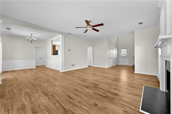a view of empty room with wooden floor and ceiling fan