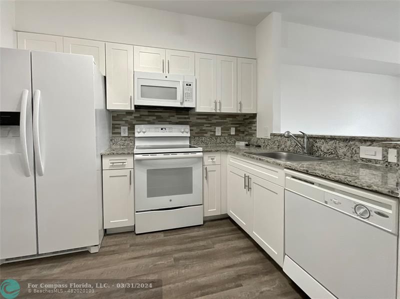 a white kitchen with granite countertop stainless steel appliances