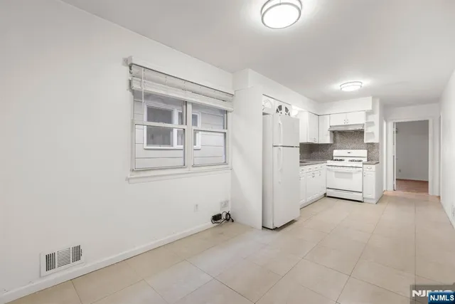 a kitchen with white cabinets and refrigerator