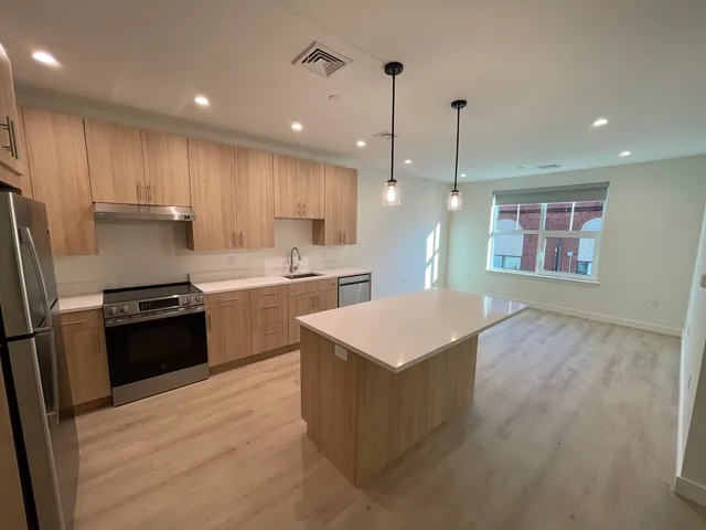 a kitchen with a refrigerator a sink and wooden floor
