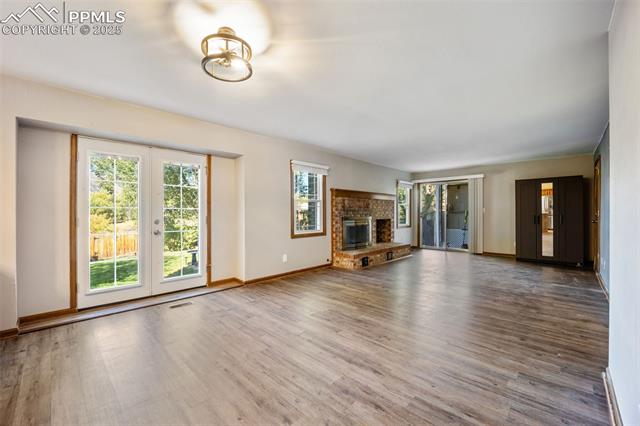 103 Saddlemountain Road Colorado Springs, CO 80919 - Photo 28 of 30 Unfurnished living room with wood finished floors, french doors, and a glass covered fireplace