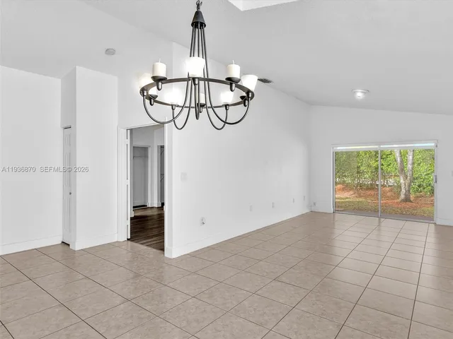 a view of empty room with window and chandelier