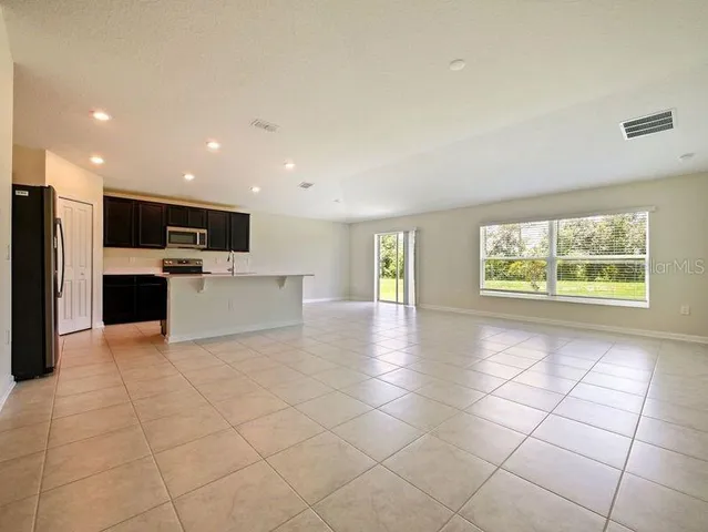 a view of a electric appliances in kitchen and empty room with wooden floor