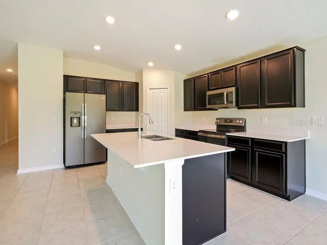 a kitchen with stainless steel appliances a stove top oven a refrigerator and a sink with wooden floor