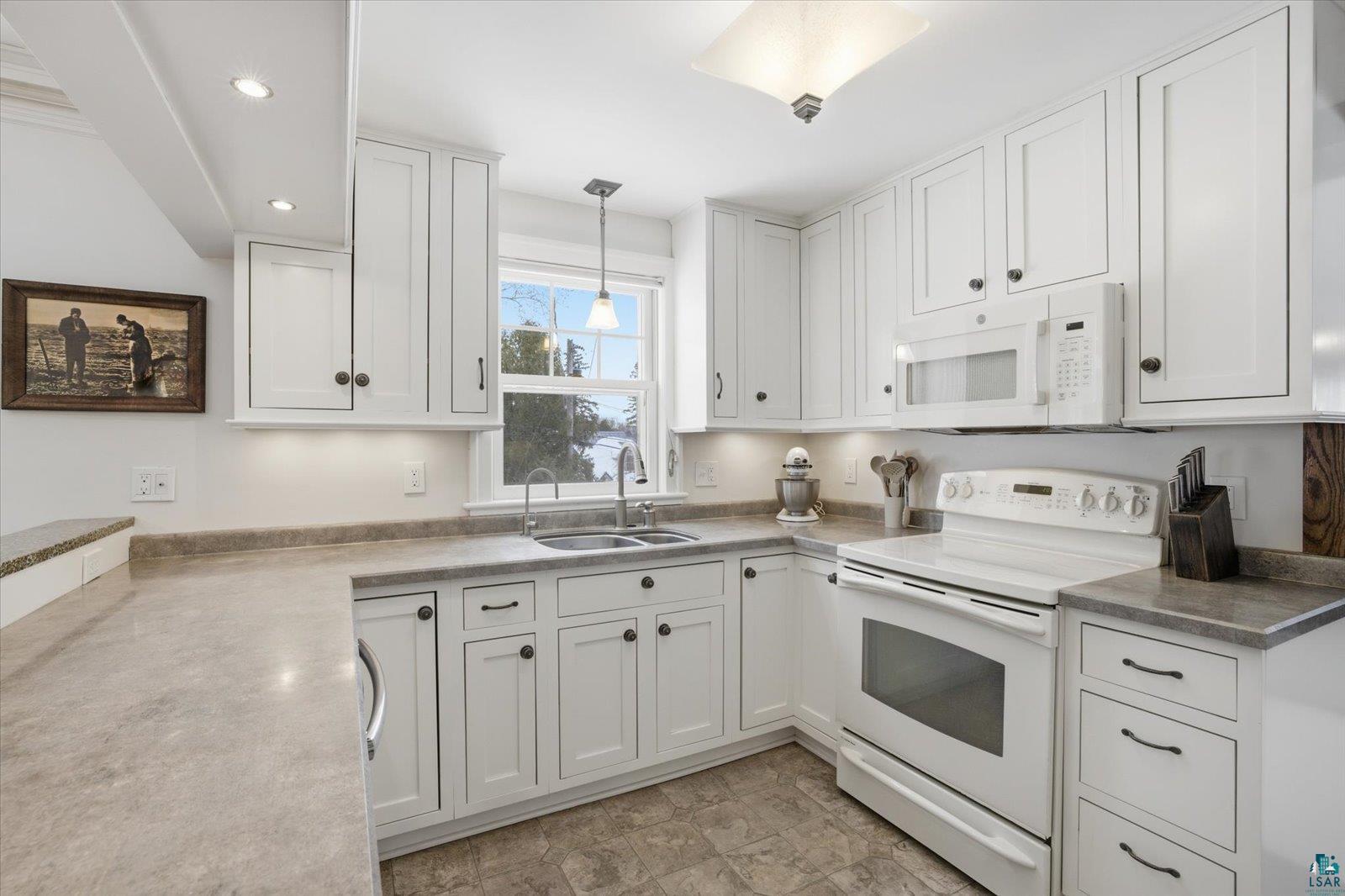 2201 Vermilion Road Duluth, MN 55803 - Photo 17 of 79 Kitchen with white appliances, white cabinetry, decorative light fixtures, and light countertops