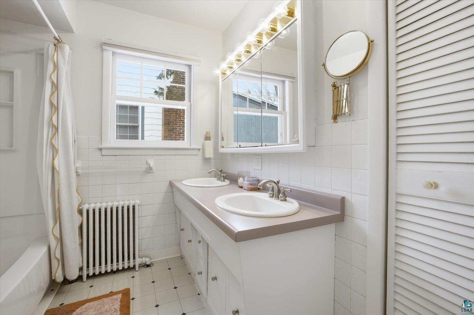 2201 Vermilion Road Duluth, MN 55803 - Photo 25 of 79 Full bathroom with radiator heating unit, double vanity, tile walls, a closet, and shower / tub combo