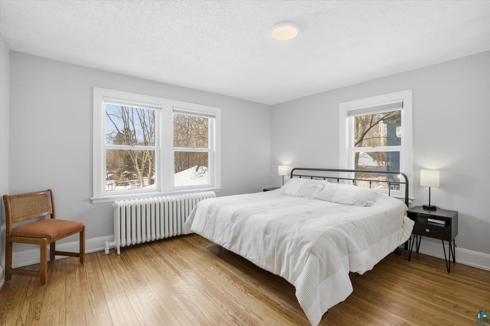 2201 Vermilion Road Duluth, MN 55803 - Photo 27 of 79 Bedroom featuring radiator, light wood-style floors, and a textured ceiling