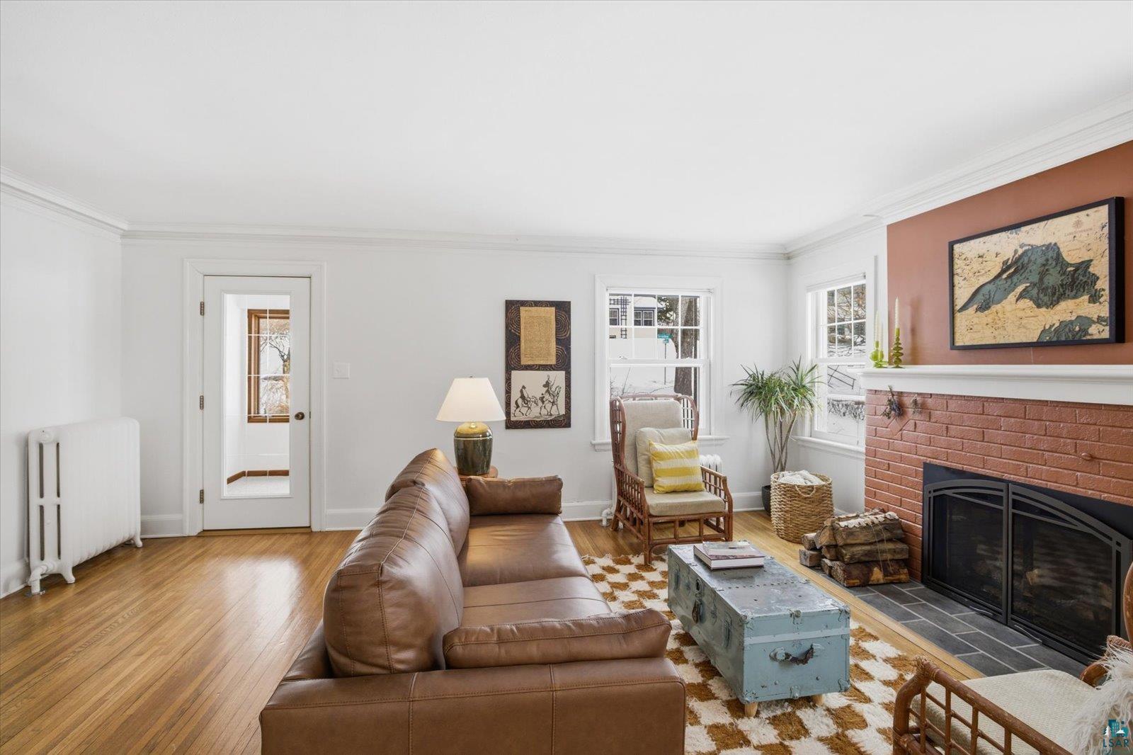 2201 Vermilion Road Duluth, MN 55803 - Photo 6 of 79 Living area featuring radiator, a brick fireplace, crown molding, and wood finished floors
