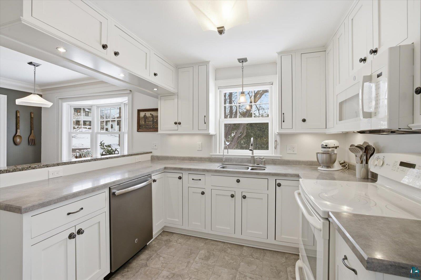 2201 Vermilion Road Duluth, MN 55803 - Photo 8 of 79 Kitchen featuring white appliances, white cabinetry, a peninsula, and hanging light fixtures
