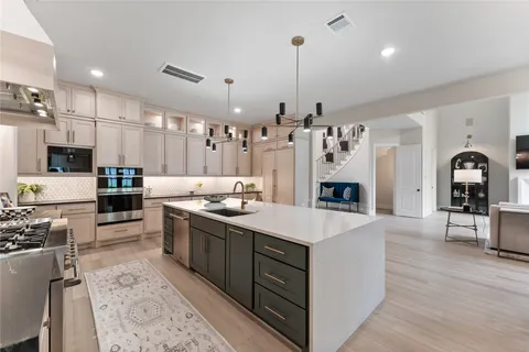 a large kitchen with stainless steel appliances kitchen island granite countertop a sink a stove and a wooden floors