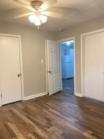 an empty room with wooden floor and a ceiling fan