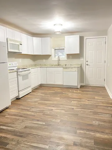 a kitchen with granite countertop white cabinets and white appliances