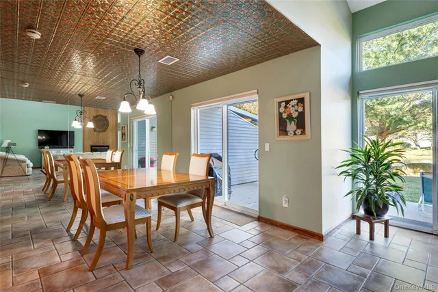 a dining room with furniture a floor to ceiling window and potted plants