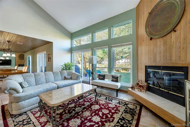 a living room with furniture a rug a fireplace and a large window