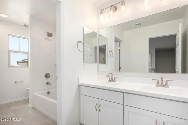 a bathroom with a double vanity sink a mirror and a bathtub