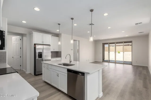 a large white kitchen with a refrigerator a sink stainless steel appliances and cabinets