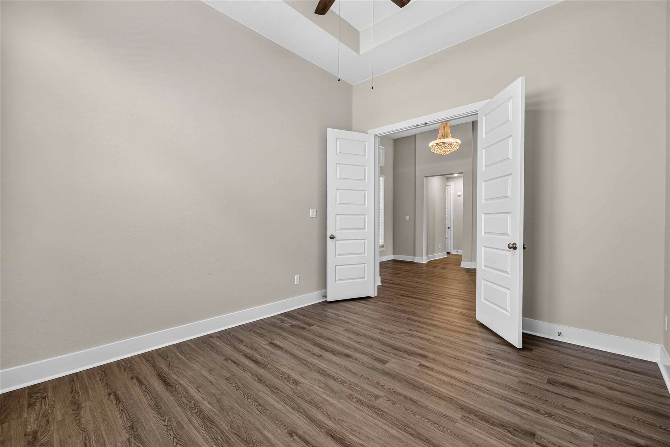 605 A Mallow Road Leander, TX 78641 - Photo 7 of 29 Hardwood-style flooring extends through an adaptable room, leading to a vibrant entry area with a sparkling chandelier.
