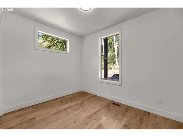 a view of an empty room with wooden floor and closet area