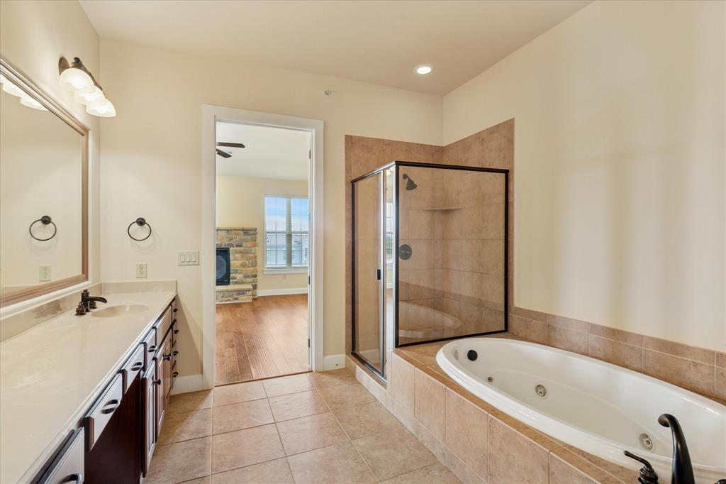 610 Via Ravello, Unit 410 Irving, TX 75039 - Photo 20 of 28 a bathroom with a tub a sink a mirror and a shower