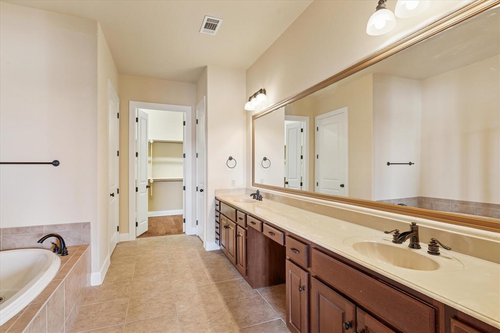 610 Via Ravello, Unit 410 Irving, TX 75039 - Photo 21 of 28 a spacious bathroom with a sink double vanity granite tub shower and a mirror