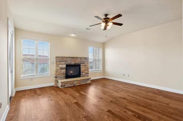 an empty room with windows fireplace and wooden floor