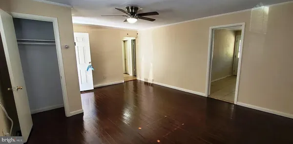 an empty room with wooden floor and a ceiling fan