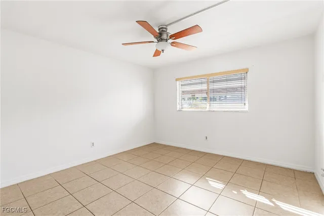 an empty room with ceiling fan and window