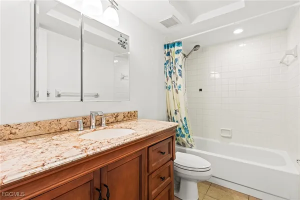 a bathroom with a granite countertop sink a toilet and shower
