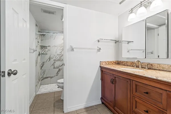 a bathroom with a granite countertop sink a toilet and shower