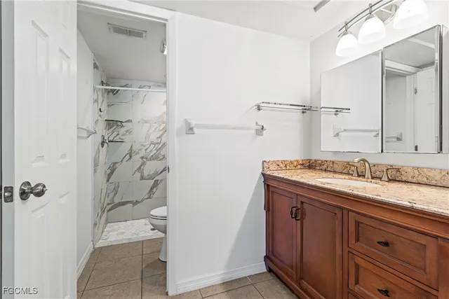 a bathroom with a granite countertop sink a toilet and shower