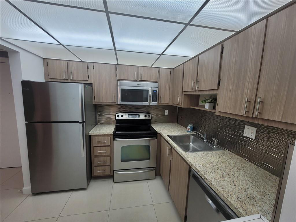 a kitchen with a sink a refrigerator a microwave and cabinets