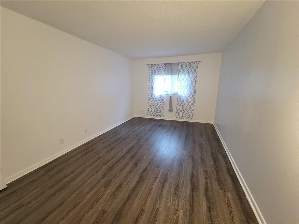 251 South Cypress Road, Unit 112 Pompano Beach, FL 33060 - Photo 7 of 20 an empty room with wooden floor and windows