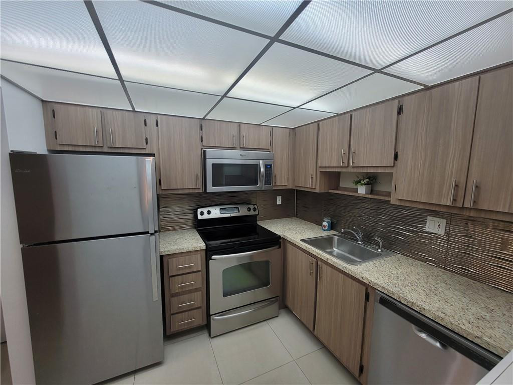 251 South Cypress Road, Unit 112 Pompano Beach, FL 33060 - Photo 9 of 20 a kitchen with stainless steel appliances granite countertop a refrigerator a stove a sink and a microwave