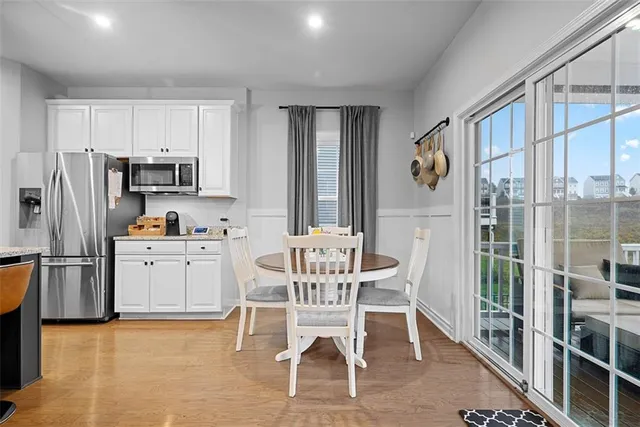 a kitchen with stainless steel appliances a refrigerator a stove a dining table and chairs