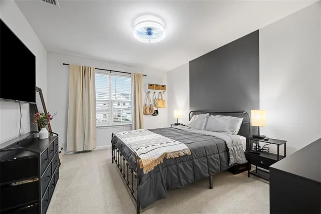 a bedroom with a bed and a flat tv screen on dresser