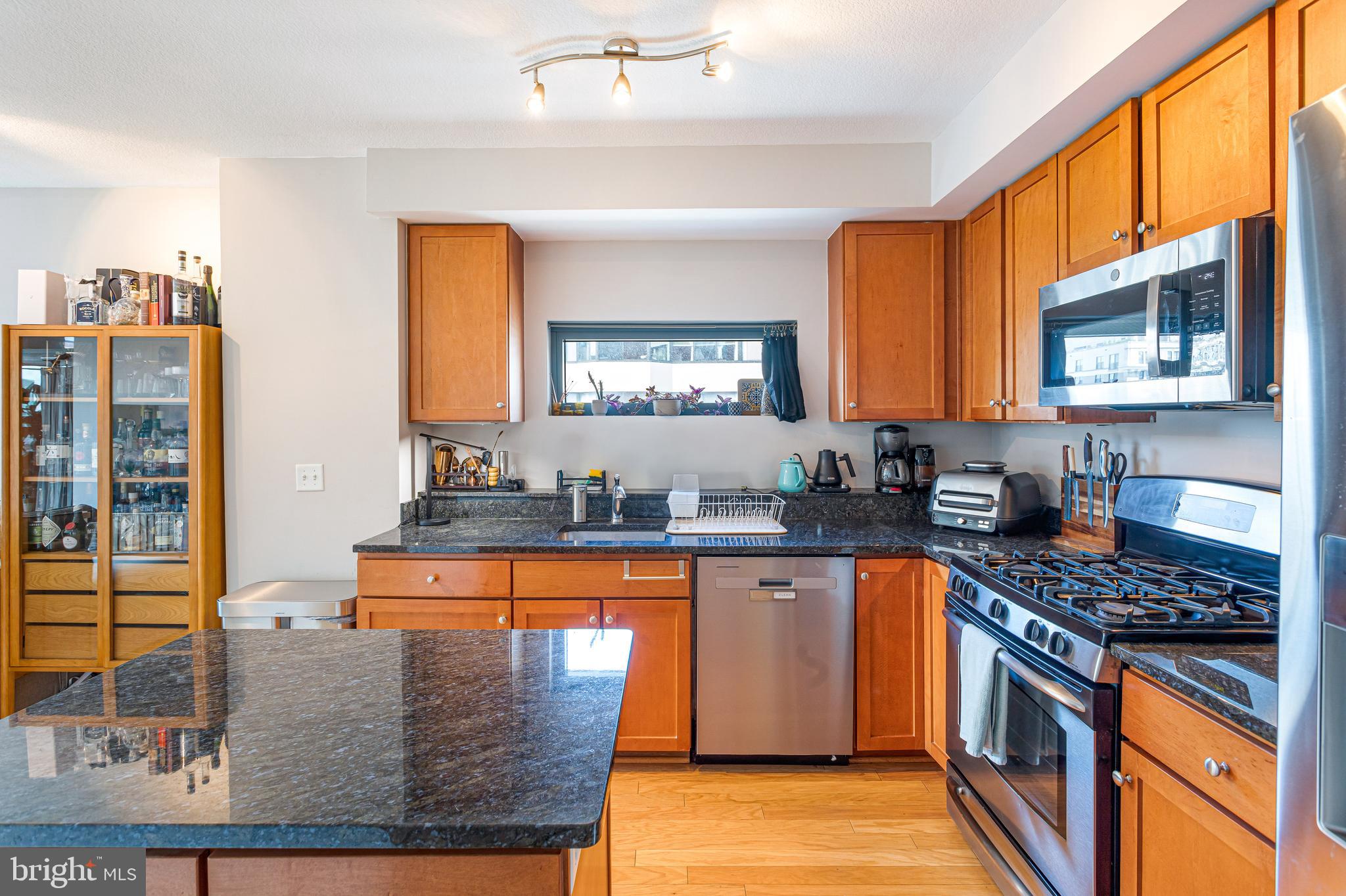 1117 10th Street Northwest, Unit 804 Washington, DC 20001 - Photo 14 of 46 a kitchen with stainless steel appliances granite countertop a stove a sink and a microwave