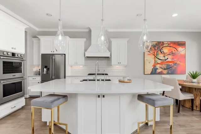 a kitchen with stainless steel appliances granite countertop a sink a stove a refrigerator and chairs with wooden floor