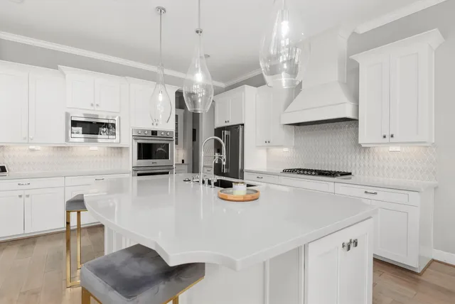 a kitchen with stainless steel appliances a stove a sink a microwave a refrigerator a stove and white cabinets