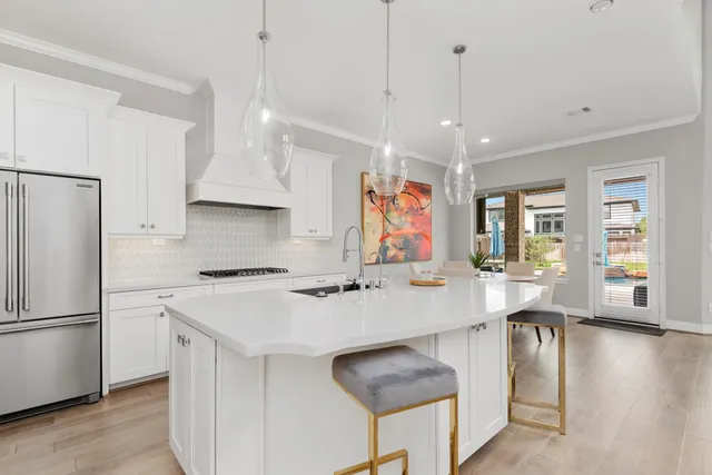 a kitchen with stainless steel appliances granite countertop a refrigerator a sink dishwasher a stove and a dining table with wooden floor